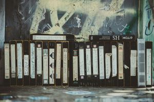VHS tapes arranged vertically, going from left to right, against a graffiti backdrop.