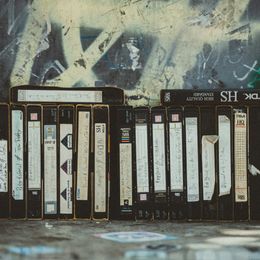 VHS tapes arranged vertically, going from left to right, against a graffiti backdrop.