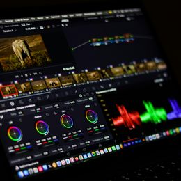 A laptop displaying the color correction page of a video editing software